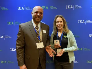 A man in a tan suit poses with a woman in a green cardigan