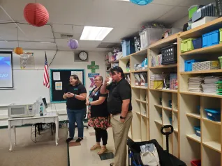 Three people laugh while speaking to a group