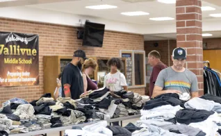 People browse through clothes piled on tables