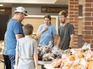 A family looks at food piled on tables