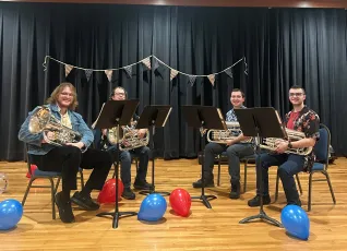 Horn musicians seated onstage