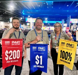 Two men and one woman holding signs with donation totals