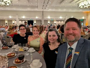 A group of people pose for a selfie at a gala dinner. 