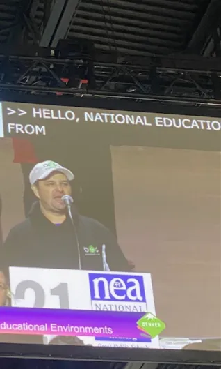 A man in a white hat speaks at a podium