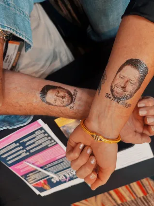 Two arms with temporary tattoos of a man's head