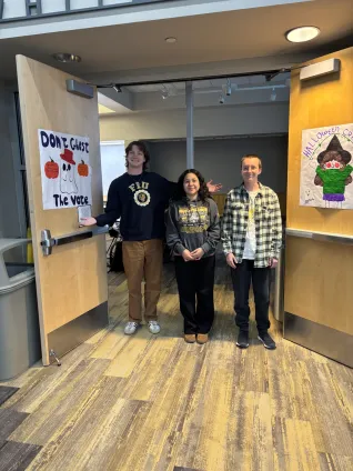 Three students stand before open doors