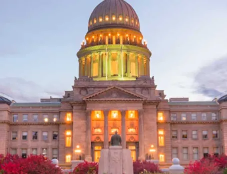 A photo of the Idaho Statehouse lit at dusk in autumn