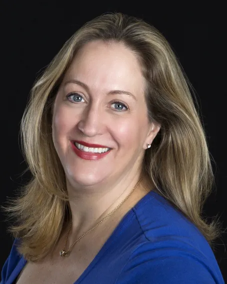 A blonde woman in a blue shirt smiling at the camera