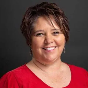 A smiling woman with short brown hair and wearing a red shirt