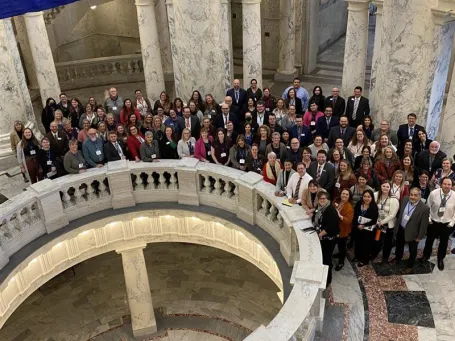 A group of people circle around the Idaho State Capitol rotunda. 