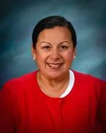 A woman with short dark hair in a red sweater smiles at the camera