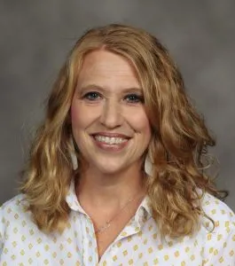 A woman with long hair smiles at the camera