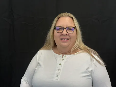 A photo of a woman in a white shirt with dark glasses and blonde hair