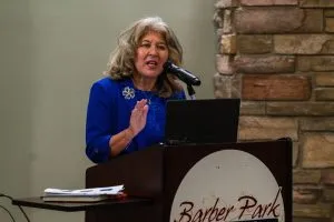 A woman in a blue suit speaks at a podium