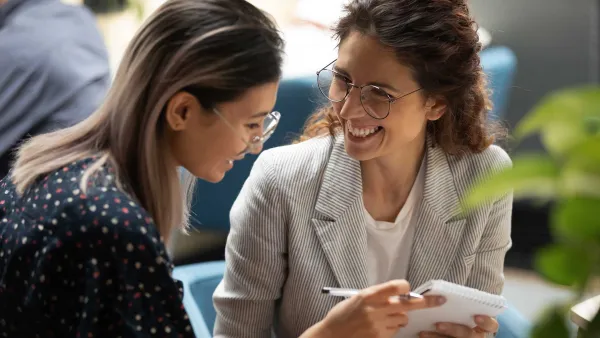 Two women looking at a notepad