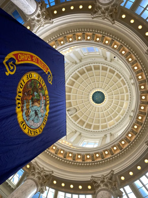 A view looking up at the Idaho Statehouse rotunda with the Idaho flag