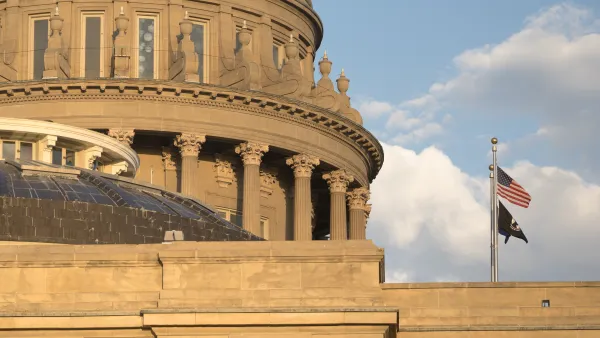 A zoomed in photo of the Idaho State Capitol with clouds in the background. 
