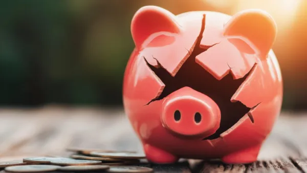 Piggy bank is cracked and broken, money lies around it. 