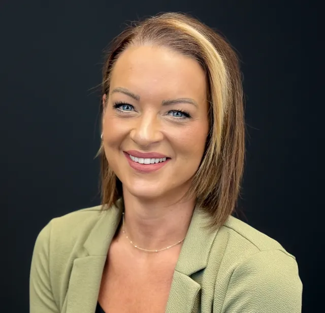 A woman with shoulder length brown hair wearing a green blazer