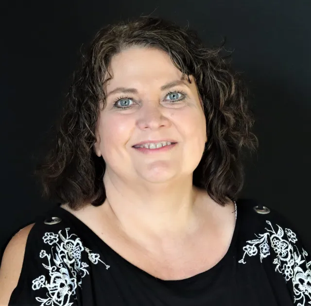 A woman with dark hair and blue eyes smiles at the camera