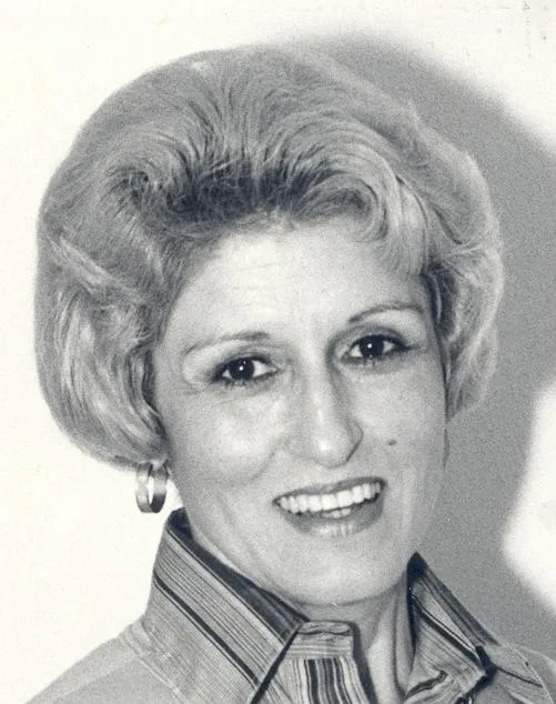 A historic photo of a woman with short hair smiling at the camera. 