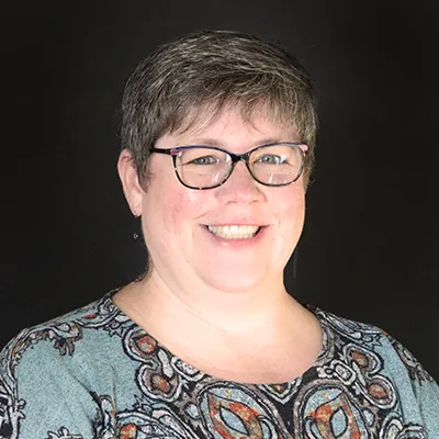 A woman with short dark hair and glasses