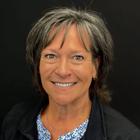 A woman with salt-and-pepper hair smiles at the camera