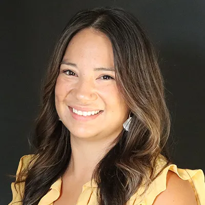 A woman with long dark hair and a yellow shirt