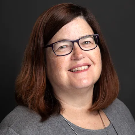 A woman with dark red hair and glasses