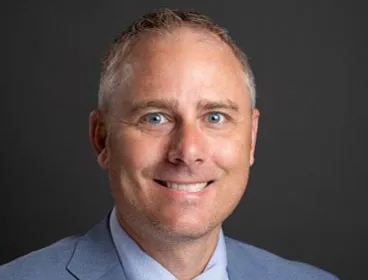 A man in a blue suit smiles at the camera