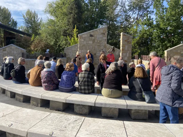 A group of people seated around the Anne Frank Memorial in Boise