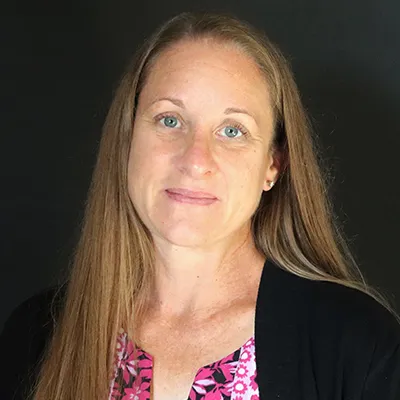 A woman with long hair wearing a black sweater smiles at the camera