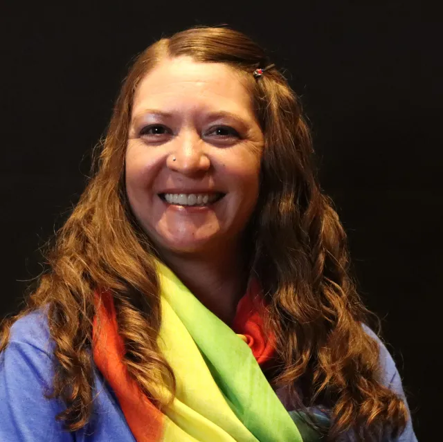 A woman with long red hair wearing a colorful scarf