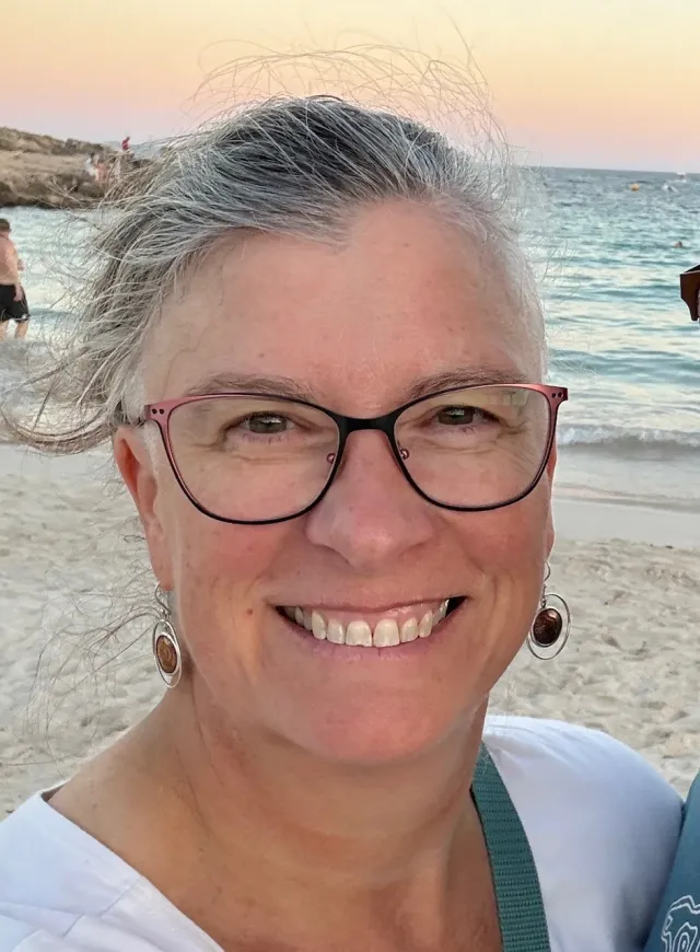 A woman on a beach smiling at the camera