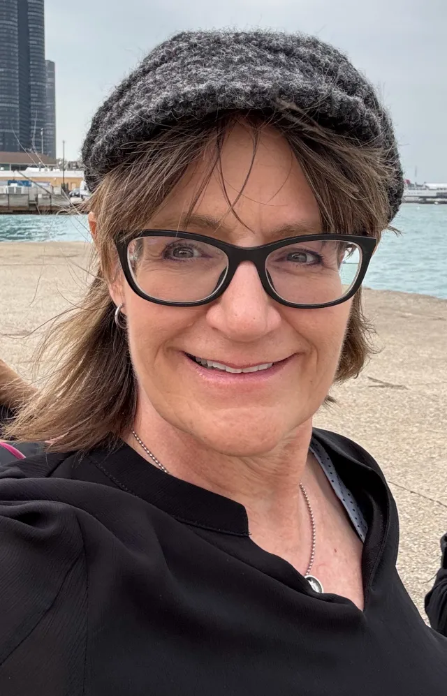 A woman on the beach wearing a hat and glasses