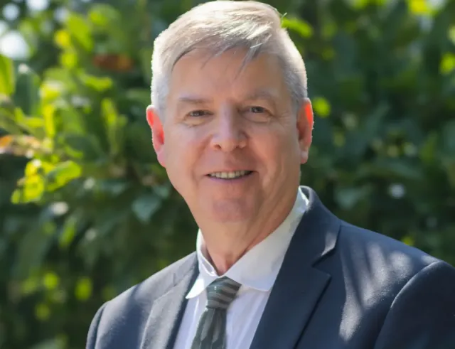 A man in a suit and tie smiles at the camera