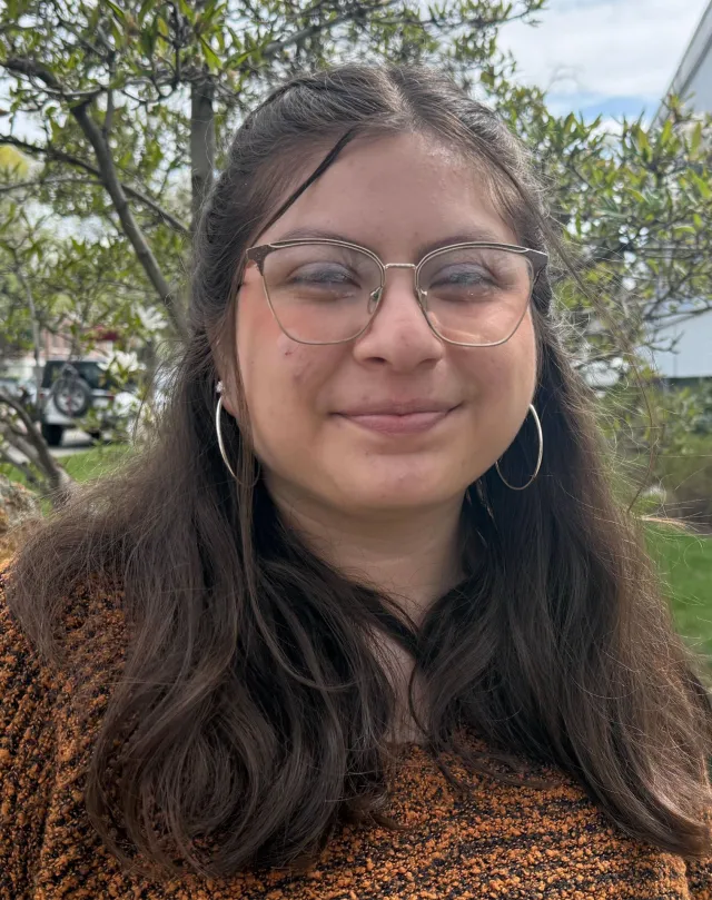 A woman with dark hair and glasses smiles at the camera